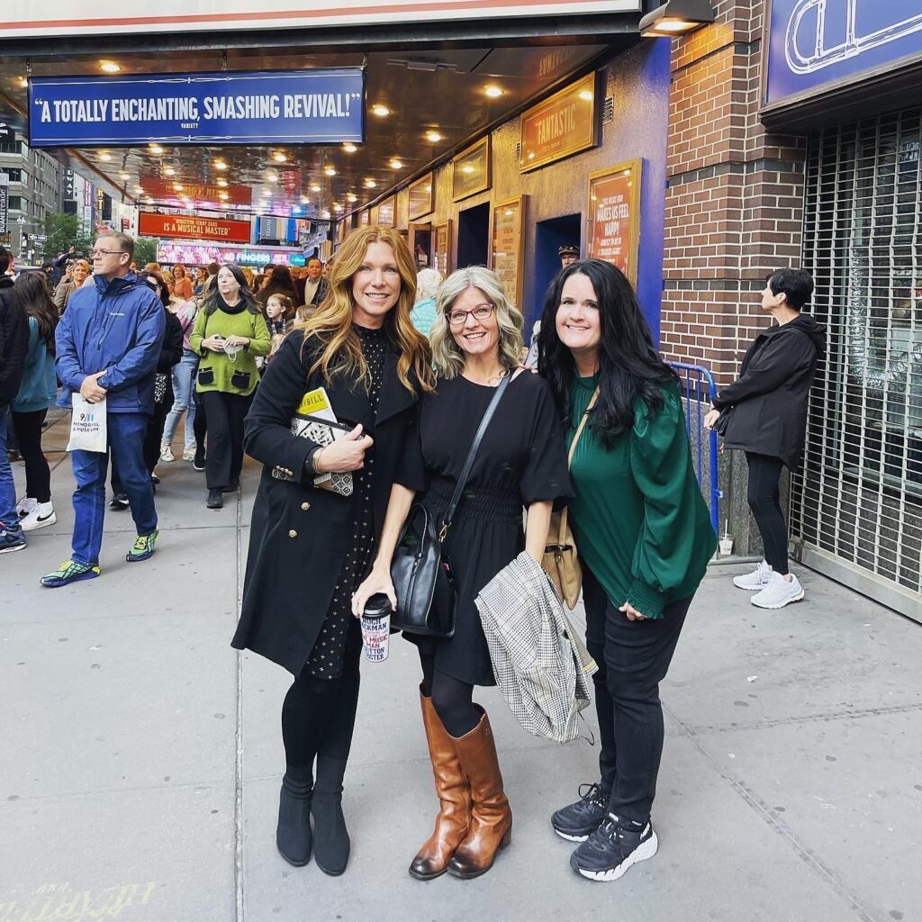 three ladies in front of a Broadway musical