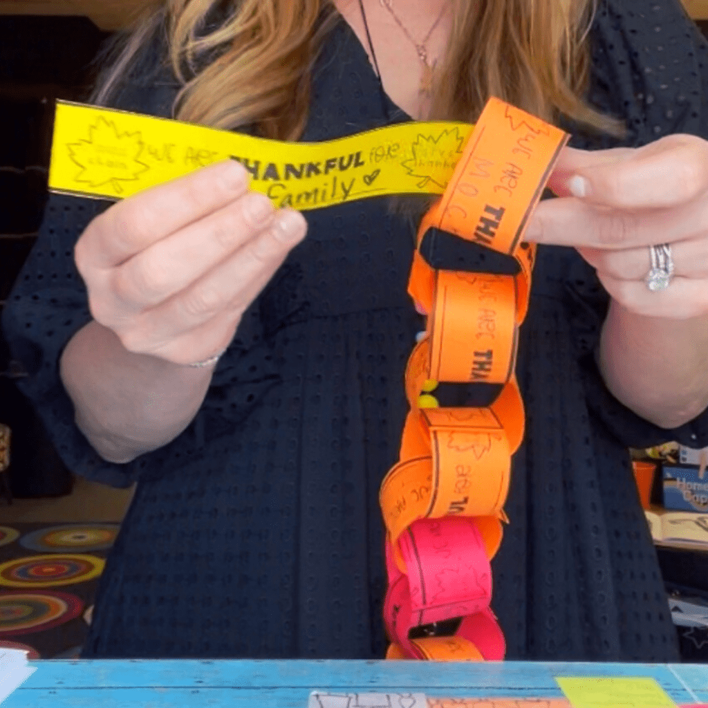 a teacher showing how to add a slip to the paper chain