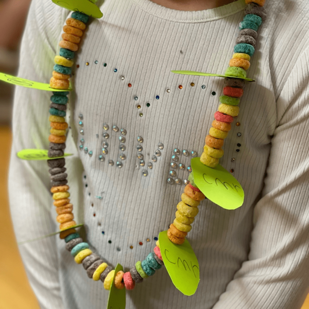 little girl with completed 100th day fruit loop necklace