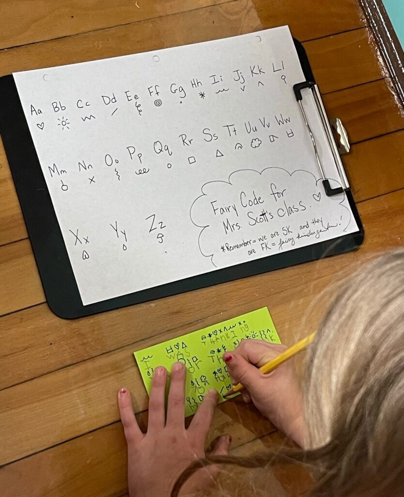 kindergartener using teacher made "fairy code" to write to the desk fairy