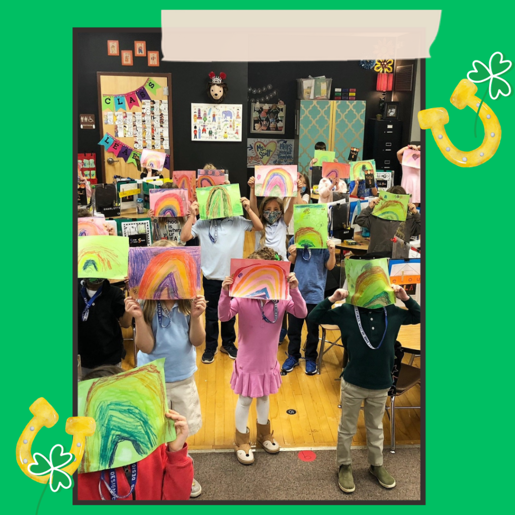 a class of kindergarteners holding up rainbow cards they've made to welcome a leprechaun