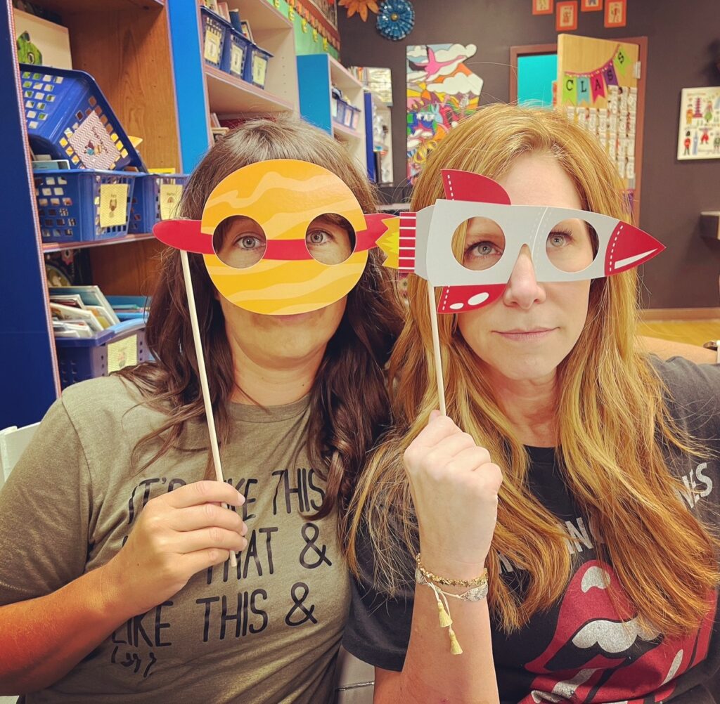 2 kindergarten teachers showing space-themed photo booth props